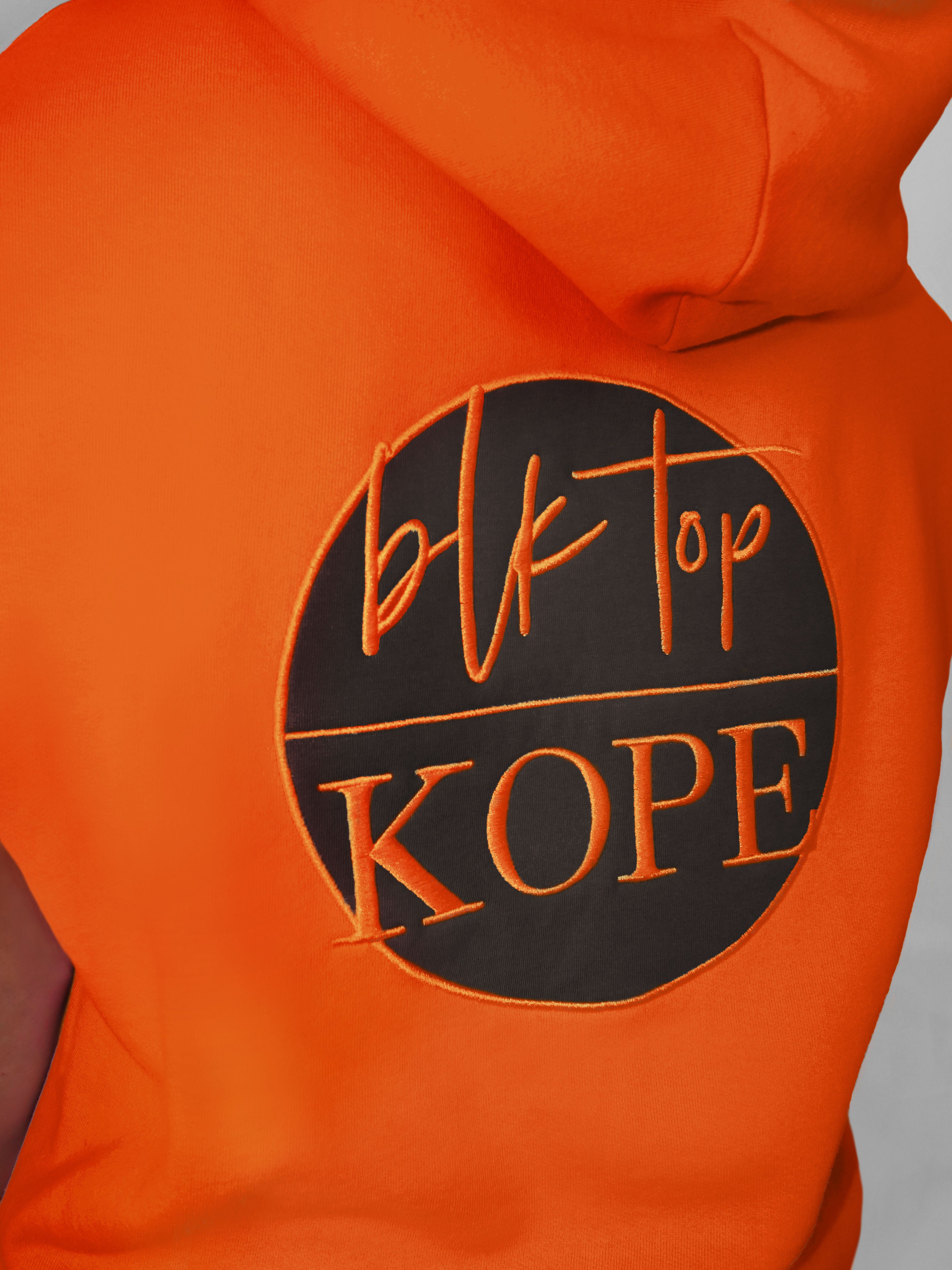 Orange sleeveless hoodie with 'BLK TOP Kope' logo on a gray background