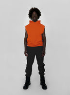 Person wearing an orange sleeveless hoodie and black sweatpants on a white background