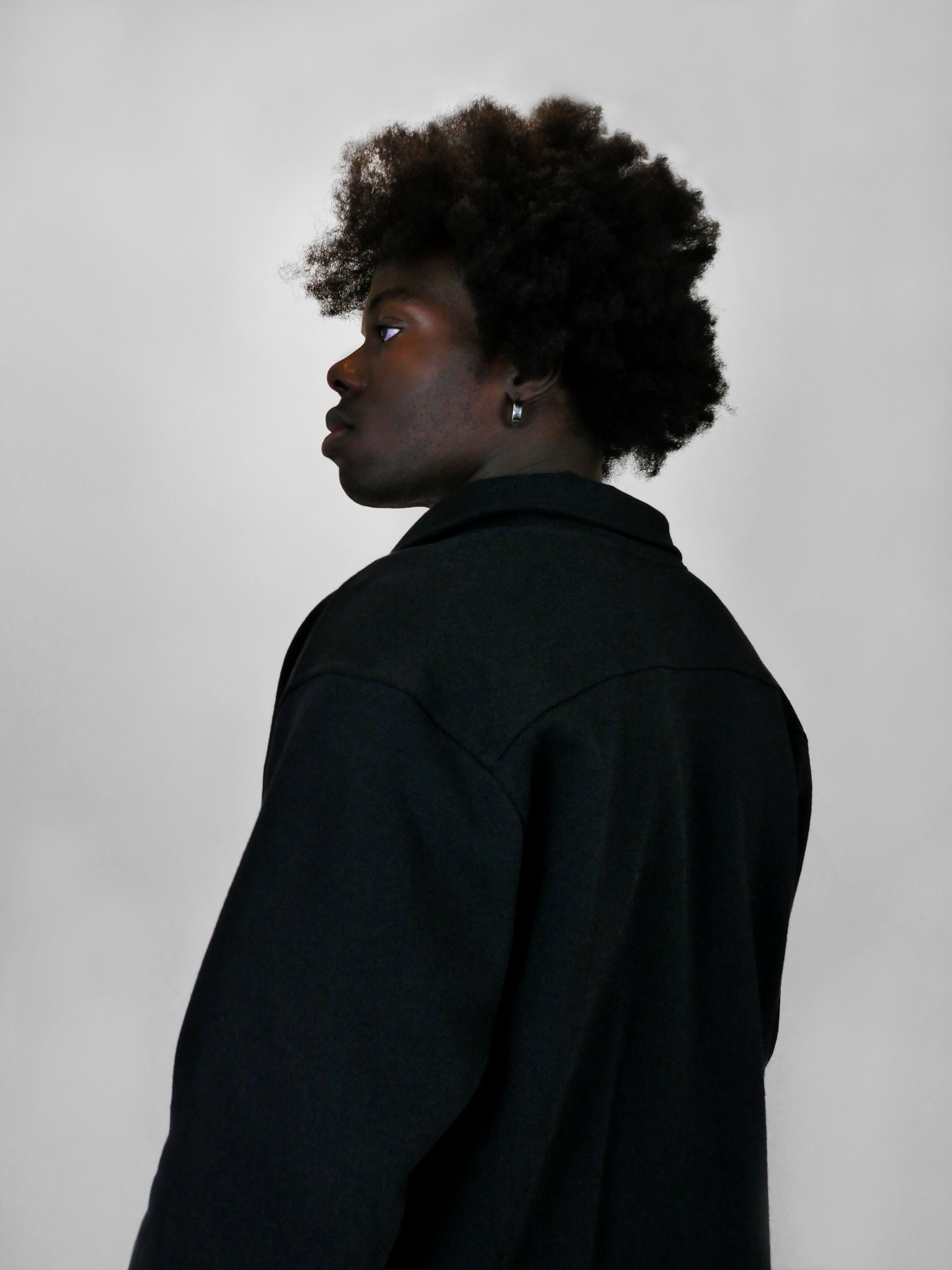 Person wearing a black snap jacket against a plain background