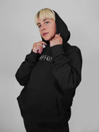 Person wearing a black hoodie with text on it against a plain background