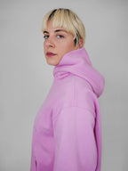 Person wearing a blush hoodie against a plain background