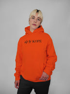 Person wearing an orange hoodie with text on a gray background