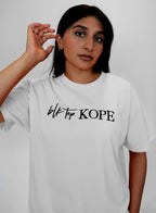 Person wearing a white t-shirt with 'blk top KOPE' text on a plain background