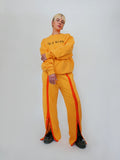 Person wearing a yellow crewneck and snap sweatpants on a white background