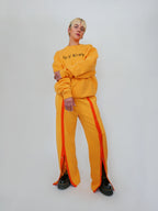 Person wearing a yellow crewneck and snap sweatpants on a white background