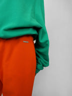 Green sweatshirt and orange sweatpants on a plain background