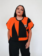 Person wearing an orange and black sweatervest on a white background