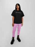 Person wearing a black t-shirt with text and blush sweatpants on a white background