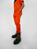 Person wearing orange sweatpants with text and black platform shoes on a white background