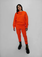 Person wearing an orange tracksuit with black boots on a white background