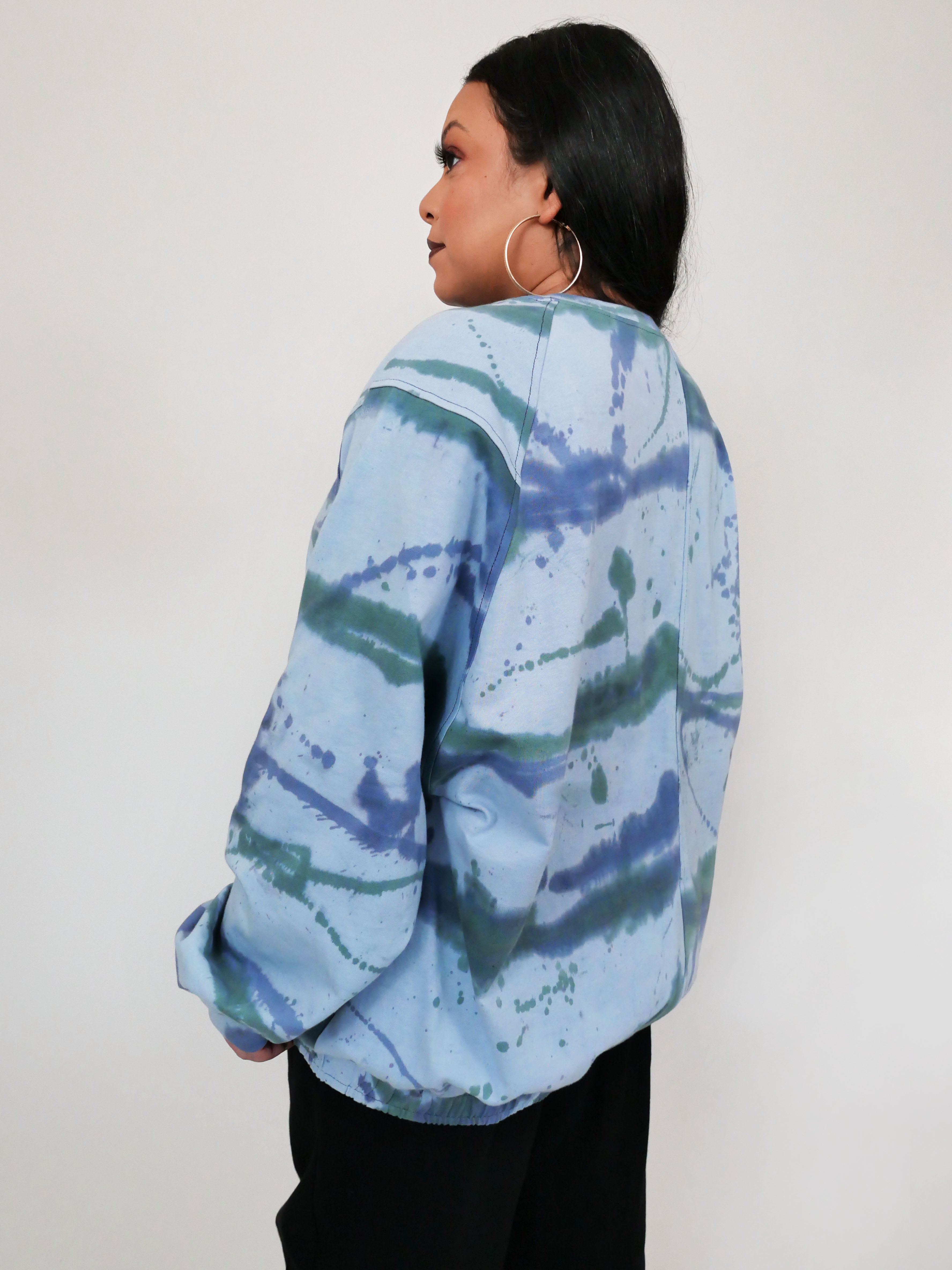 Person wearing a blue tie-dye shirt against a white background