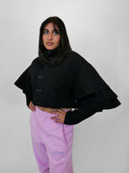 Person wearing a black volant jacket and blush sweatpants on a plain background