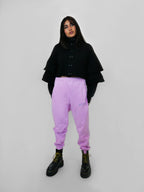 Person wearing a black volant jacket and blush sweatpants on a white background