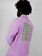 Person wearing a blush snap jacket with text on the back against a plain background