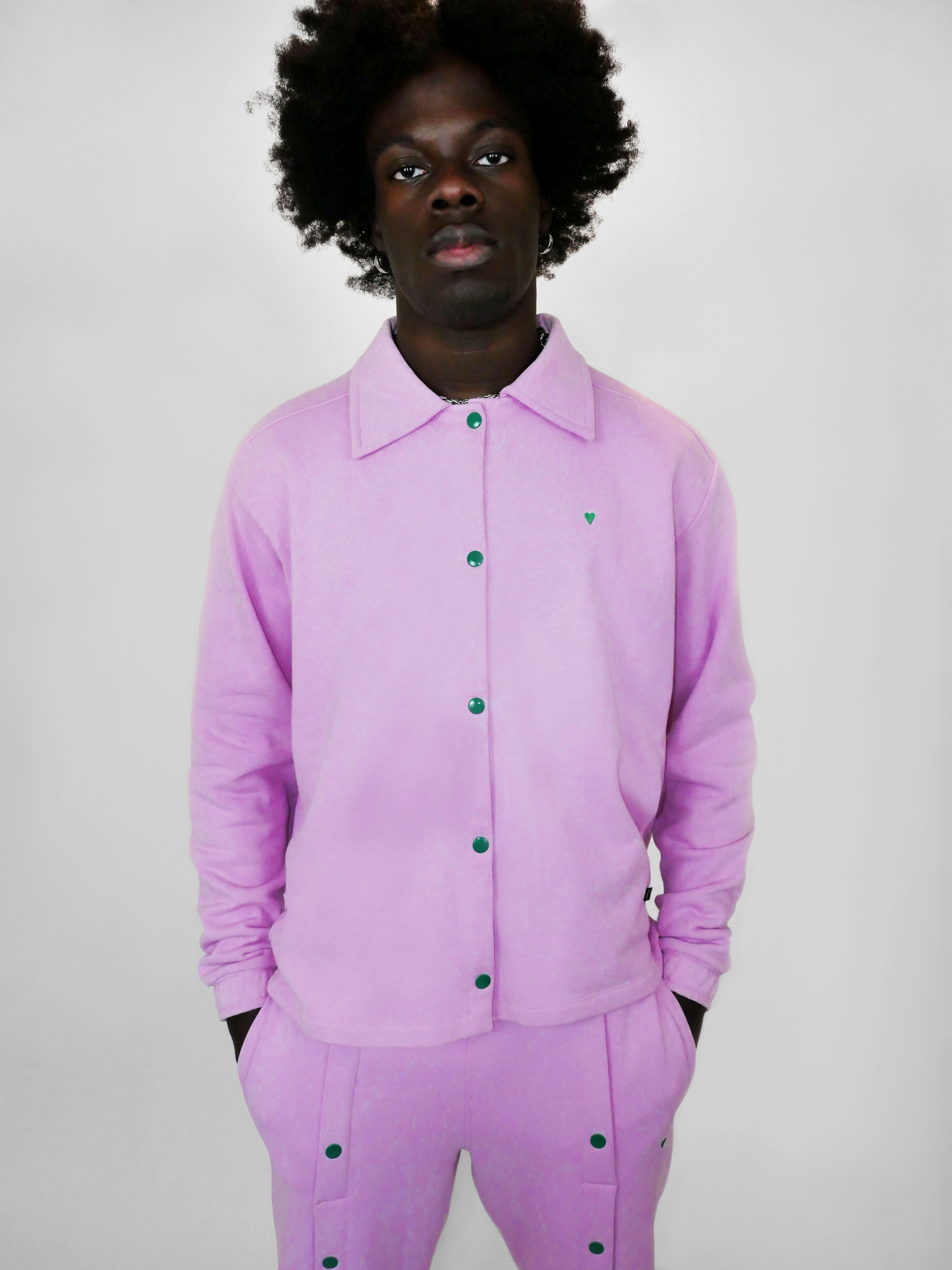 Person wearing a blush snap jacket with green snap buttons on a plain background