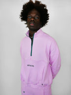 Person wearing a blush zip-up with a brand logo on a plain background