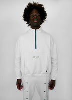 Person wearing a white zip-up with a brand logo on a plain background
