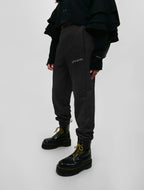 Person wearing black sweatpants with logo and black boots on a white background