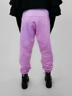 Person wearing blush sweatpants and black shoes on a plain background