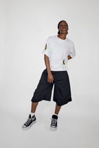 Person wearing a white t-shirt and black shorts with high-top sneakers on a white background