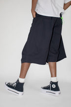 Person wearing black cargo shorts and black high-top sneakers on a white background
