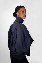 person wearing a black track jacket with matching pants shown from a side back angel