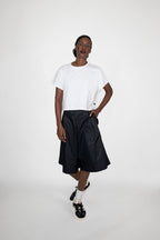 Person wearing a white t-shirt and black dress shorts on a white background
