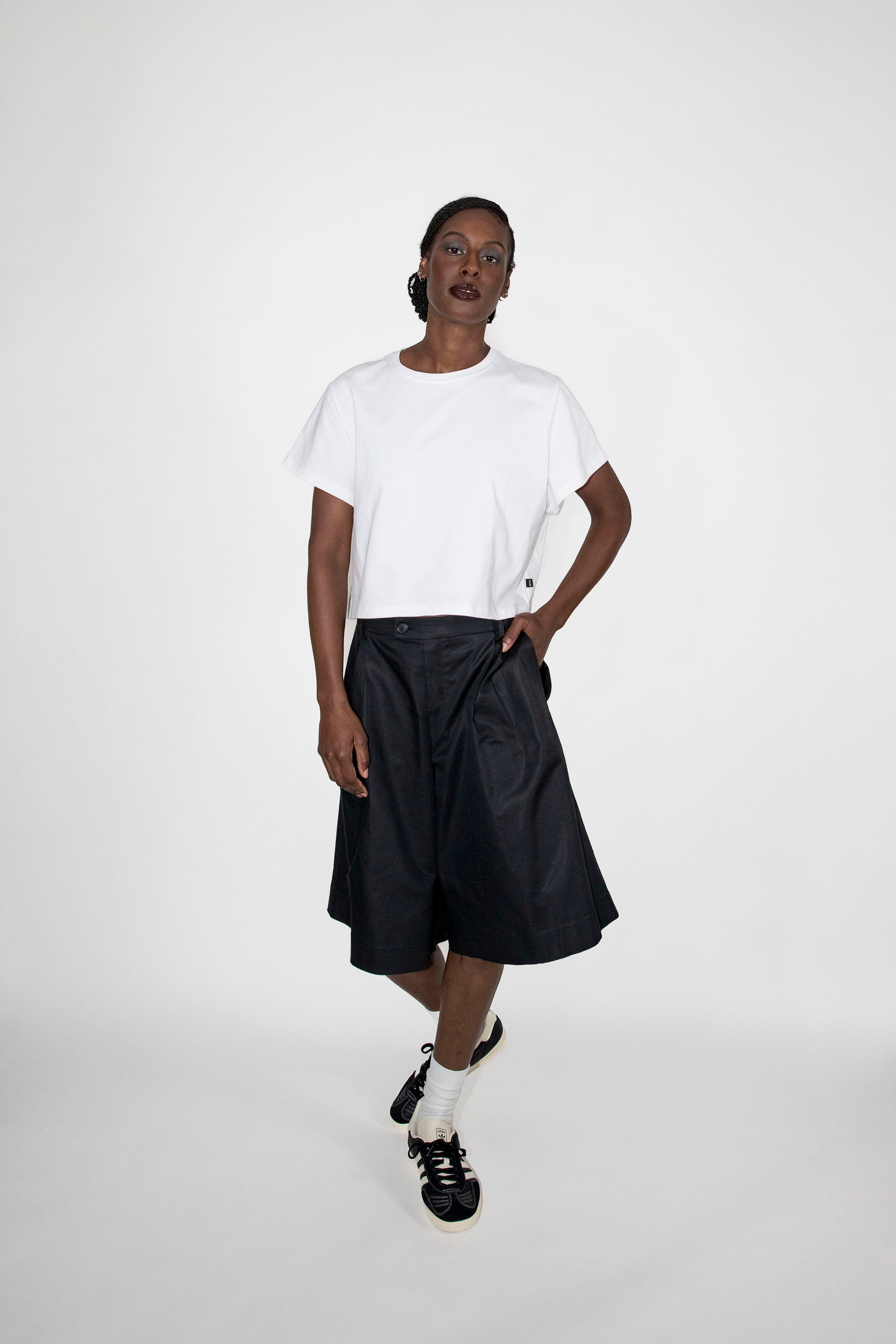 Person wearing a white t-shirt and black dress shorts on a white background