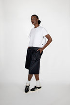 Person wearing a white t-shirt, black shorts, and black sneakers on a white background