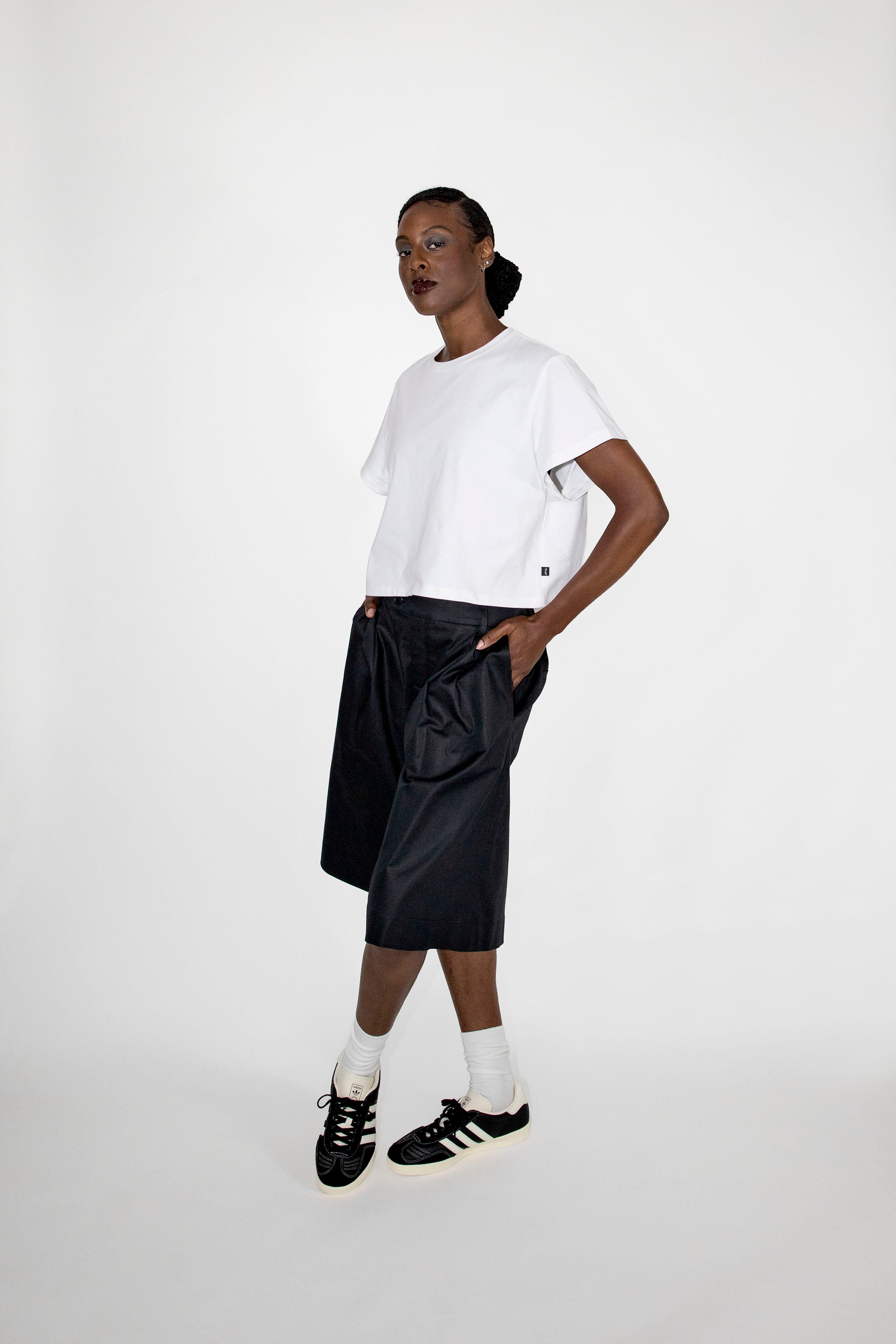 Person wearing a white t-shirt, black shorts, and black sneakers on a white background