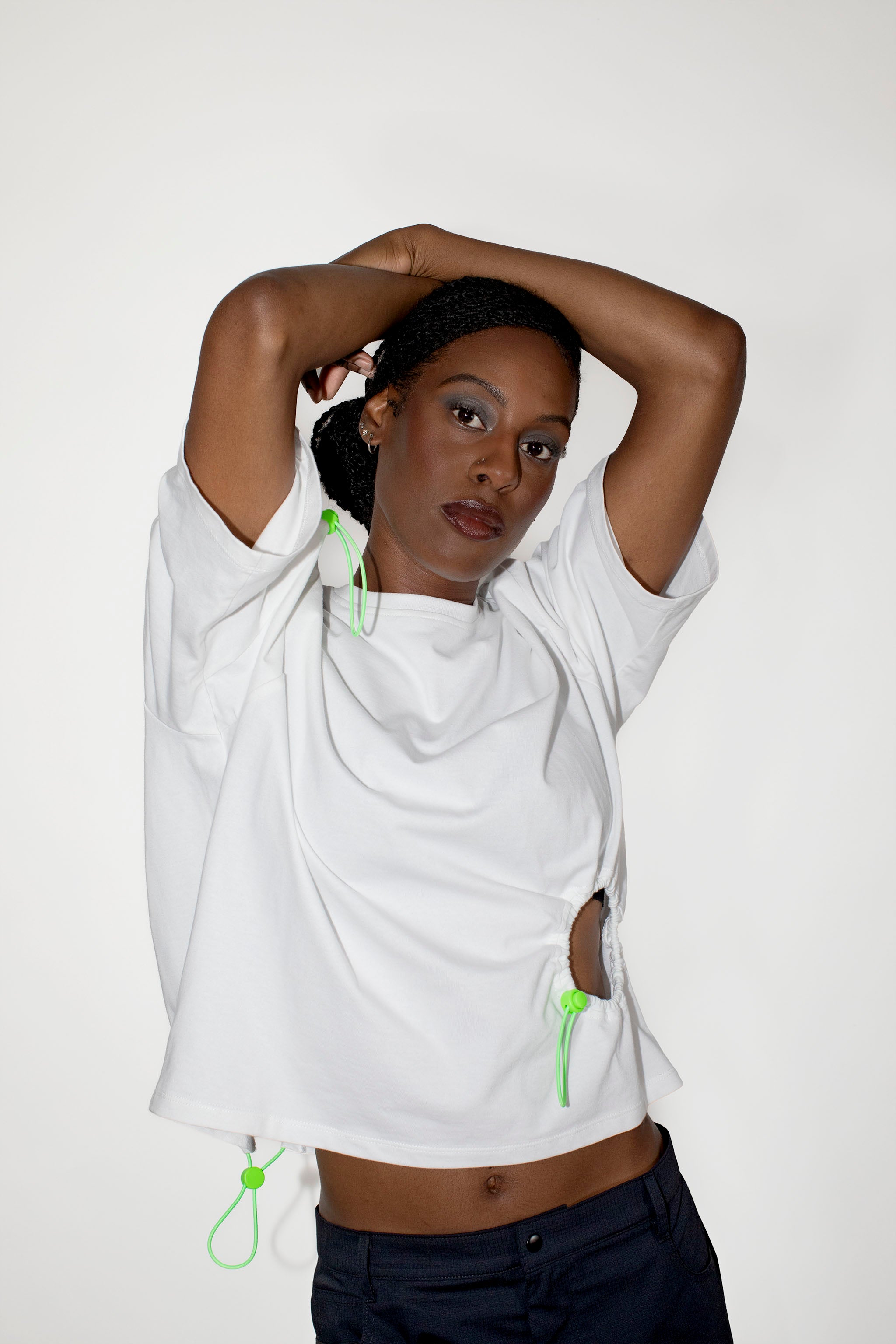 Person wearing a white shirt with green elastic strips on a plain background