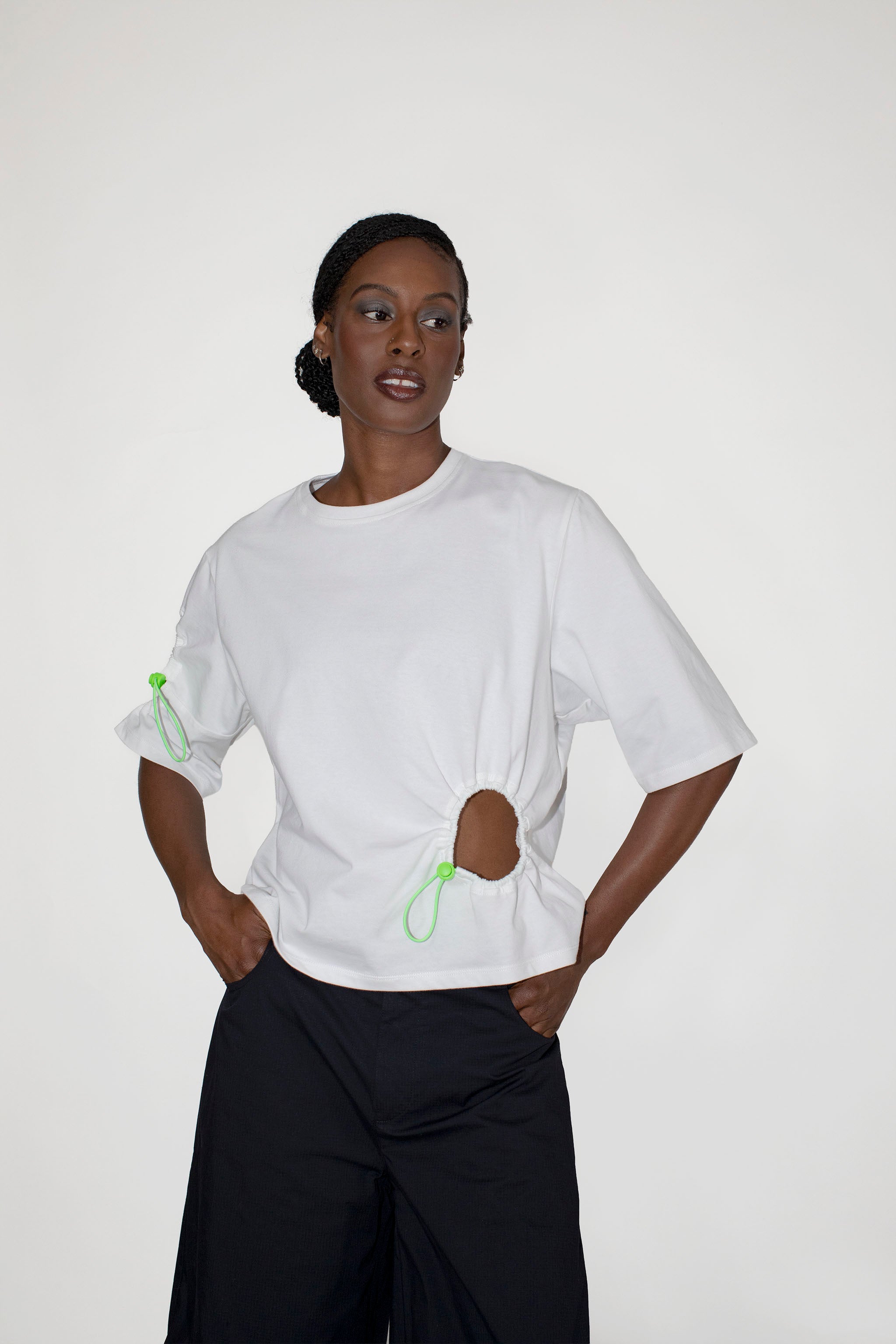 Person wearing a white t-shirt with green accents on a plain background