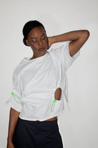 Person wearing a white t-shirt with green accents and black shorts on a plain background