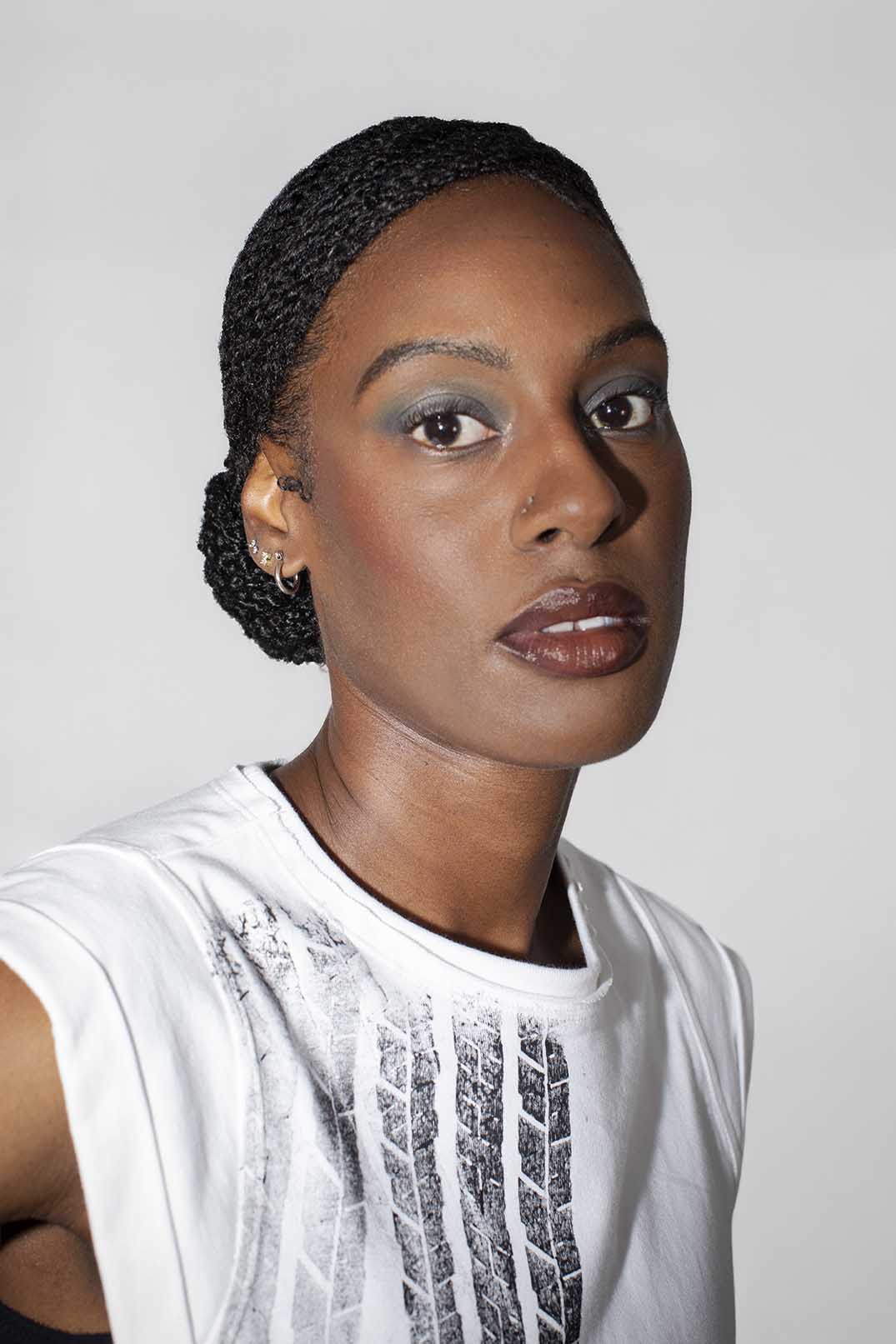 closeup of person wearing a white sleeveless top with black tire print on the front