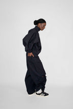person wearing matching black track jacket and pants with black and white sneakers