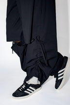 Person wearing black pants and Adidas shoes on a white background