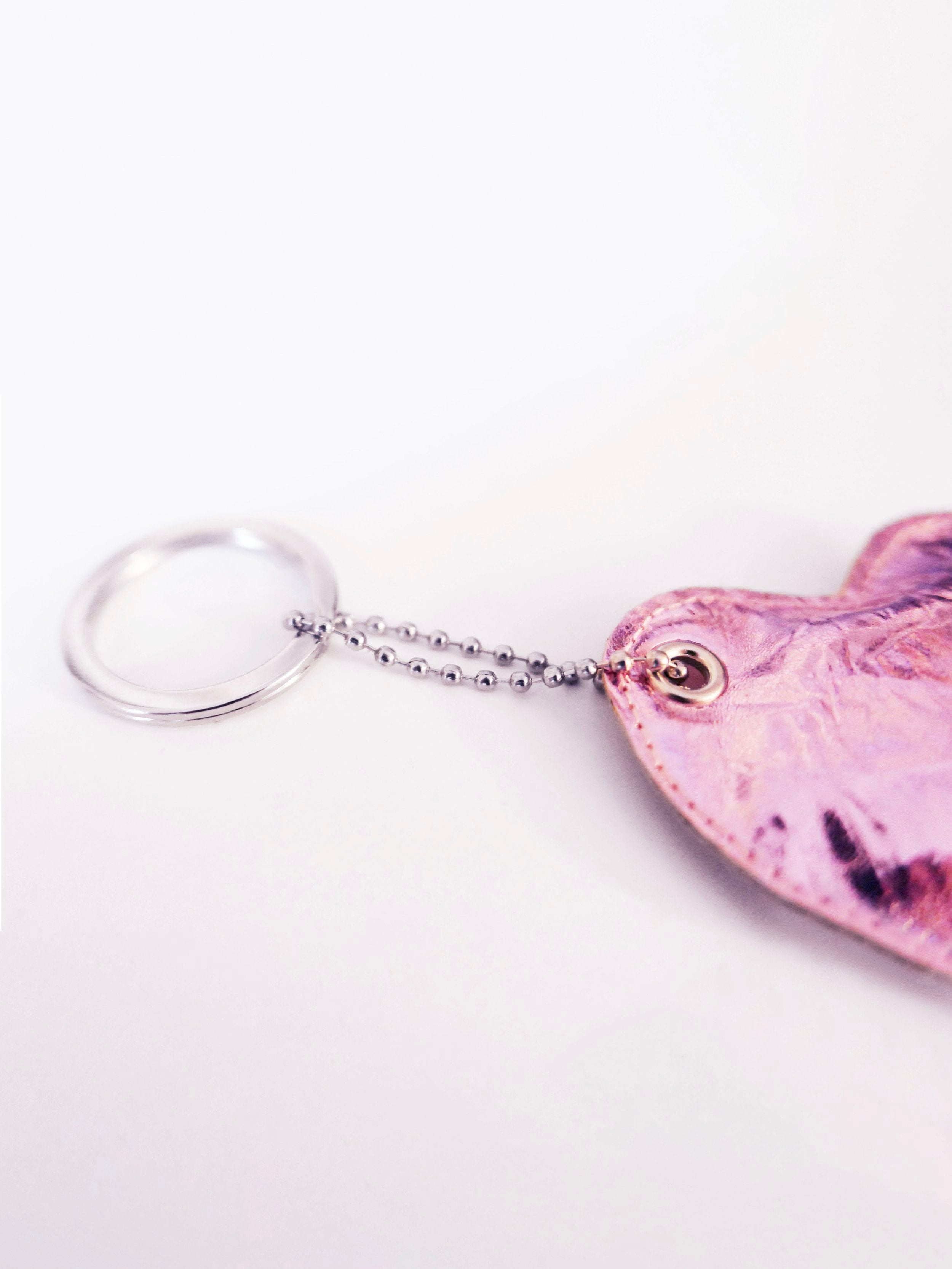 close-up of a pink heart-shaped keychain on a white background