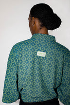 Person wearing a green patterned polo tee with a visible brand label on a white background