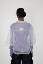 Person wearing a light purple and white mesh top with a visible brand logo on a white background
