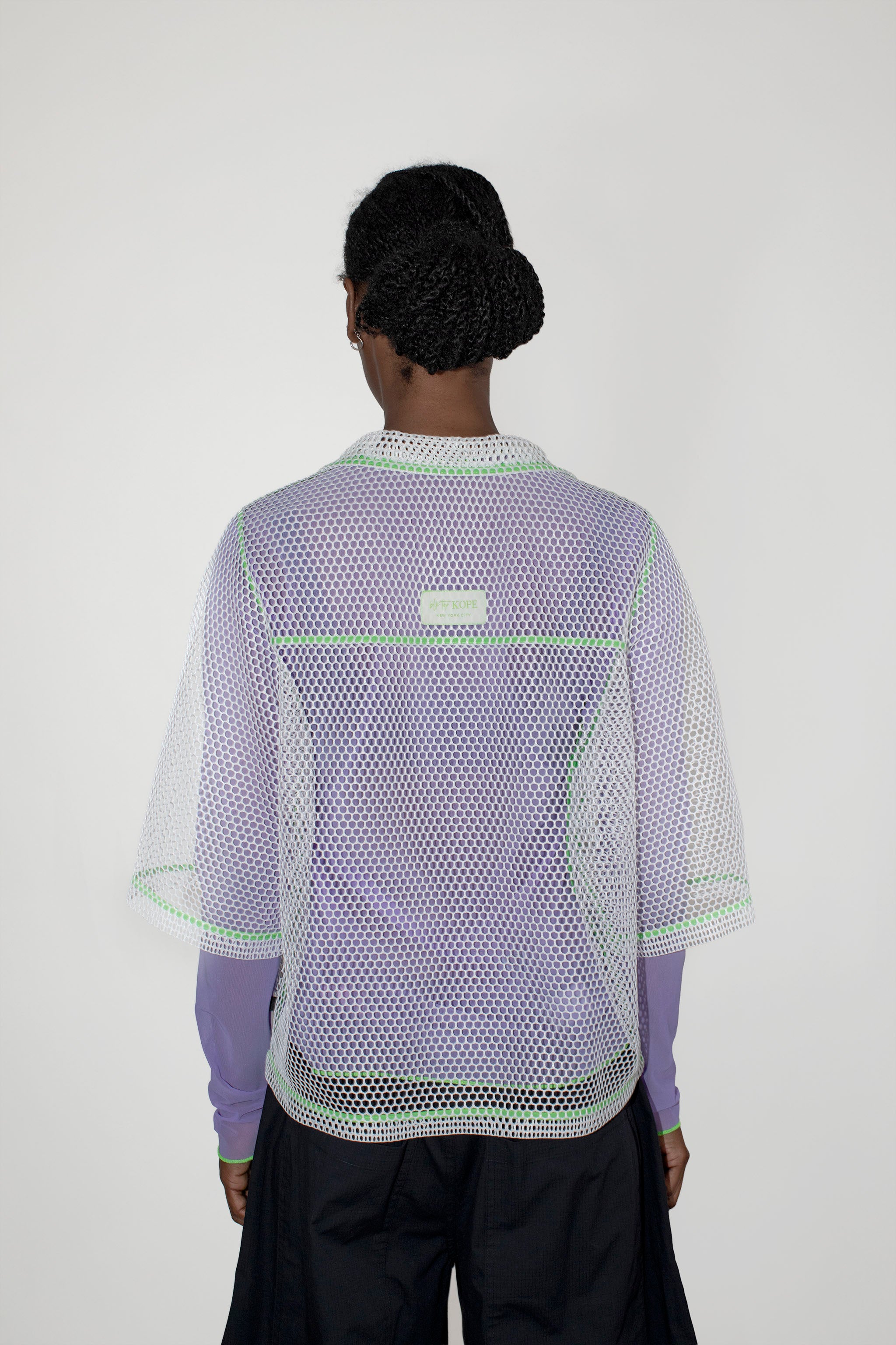 Person wearing a light purple and white mesh top with a visible brand logo on a white background