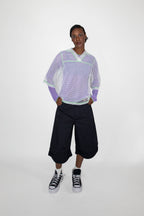 Person wearing a light purple and white mesh t-shirt with black shorts on a white background