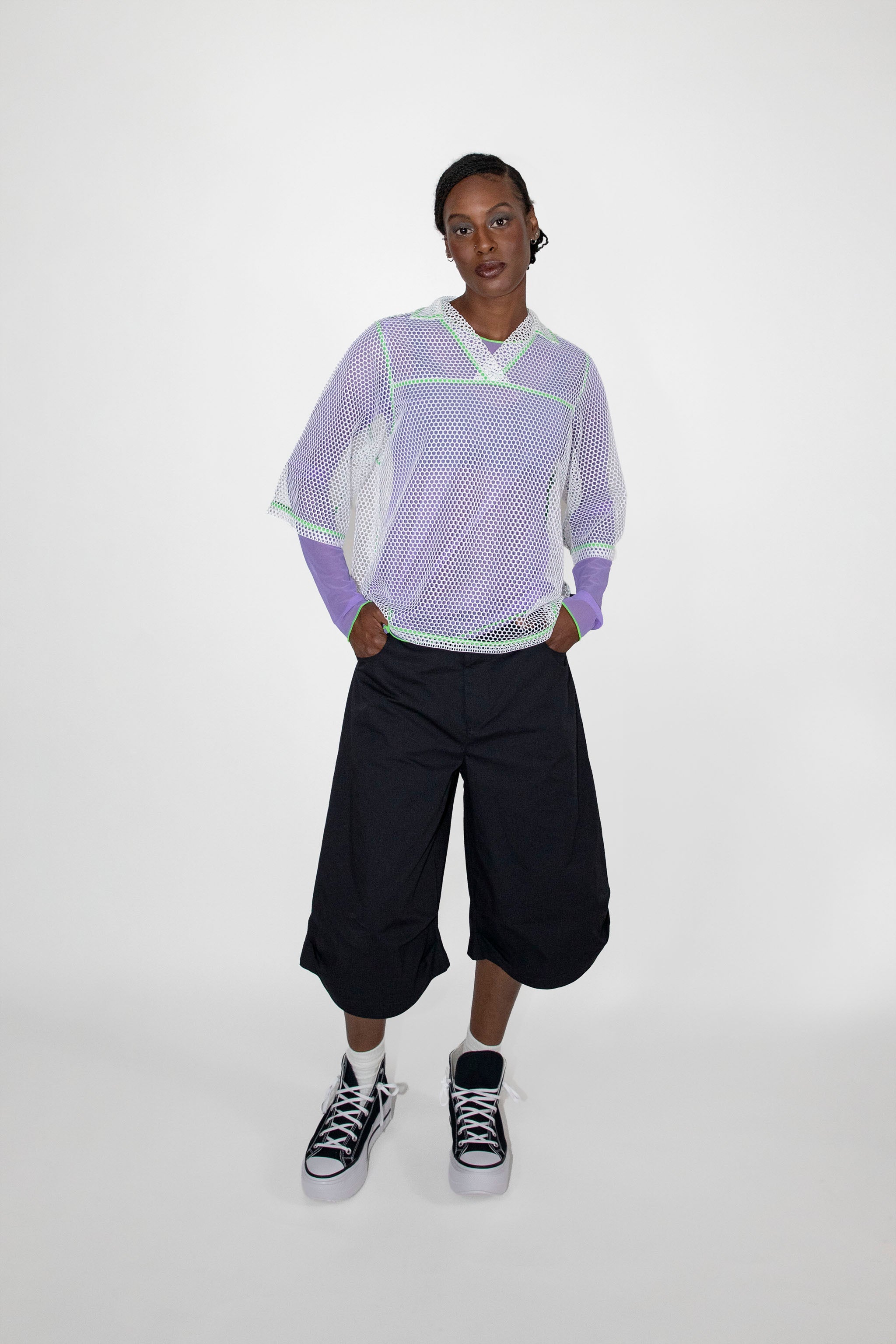 Person wearing a light purple and white mesh t-shirt with black shorts on a white background