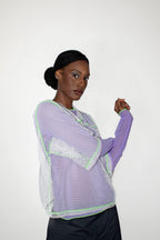 Woman wearing a light purple longsleeve with a white mesh t-shirt on a white background