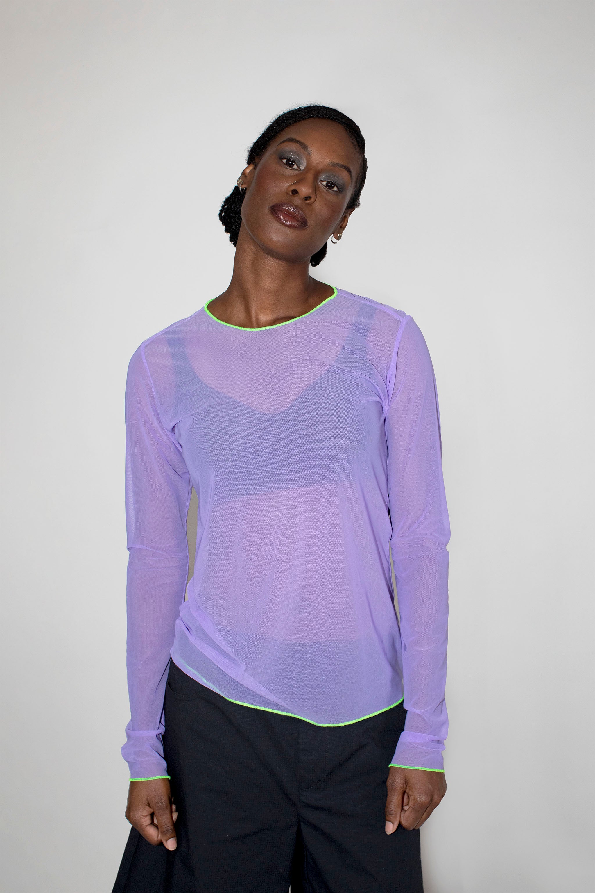 Person wearing a sheer purple long-sleeve top with a solid background