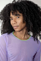 person with voluminous black curly hair wearing a sheer lavender mesh longsleeve