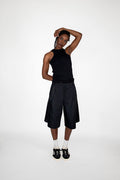 Person wearing a black sleeveless top and black shorts on a white background